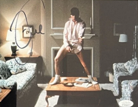 A small colour Risky Business still of Tom Cruise dancing in a shirt and socks, signed in the upper left in blue marker, with a JSA authentication sticker in the lower right corner.