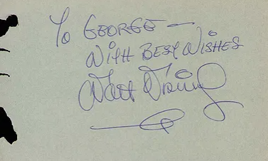 An album page inscribed in blue ink, "To George — With Best Wishes", signed Walt Disney with a flourish beneath the name.
